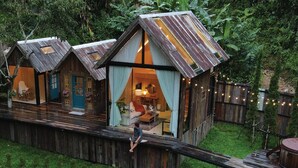 A rustic cabin-style hotel with a wooden deck and a small stream. - Morning Star Glamping (Mae On)