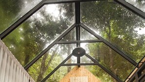A cozy, enclosed room with a sloped wooden ceiling, a bed with white bedding, a small table, and a chair. - Morning Star Glamping (Mae On)
