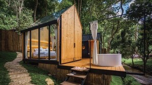 A modern wooden cabin with a glass-enclosed bedroom and a private outdoor hot tub area. - Morning Star Glamping (Mae On)
