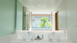 A modern bathroom with two sinks, a large mirror, and a view of a palm tree through a window. - Enjoy A Luxurious 5 Bedroom Villa (Da Nang)