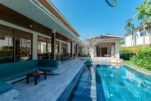 A modern pool area with a clear blue pool, a green outdoor seating area, and a well-maintained garden. - Enjoy A Luxurious 5 Bedroom Villa (Da Nang)