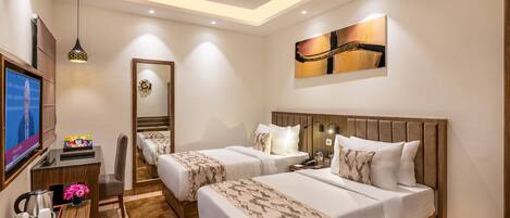 A hotel room with two beds, a TV, a desk, and a ceiling fan.