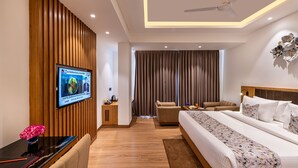 Ein modernes Hotelzimmer mit einem großen Bett, einer Couch, einem an der Wand montierten Fernseher und einer Wandverkleidung aus Holz.
