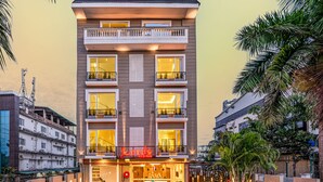 Ein mehrgeschossiges Hotel im modernen Stil, mit Balkonen inklusive Geländern und einem gut beleuchteten Eingang.