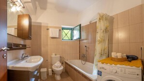Ein Badezimmer mit Waschbecken, Toilette, Badewanne und Waschmaschine.