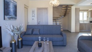 Una sala de estar moderna con un sofá gris, una mesa de centro de madera y una escalera que lleva a un nivel superior.
