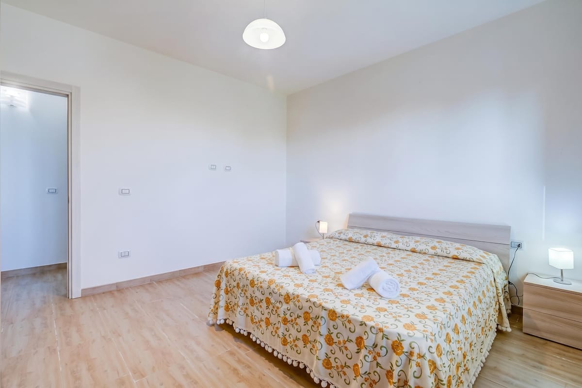 Een slaapkamer met een bed, nachtkastje en een bijpassende tafel.