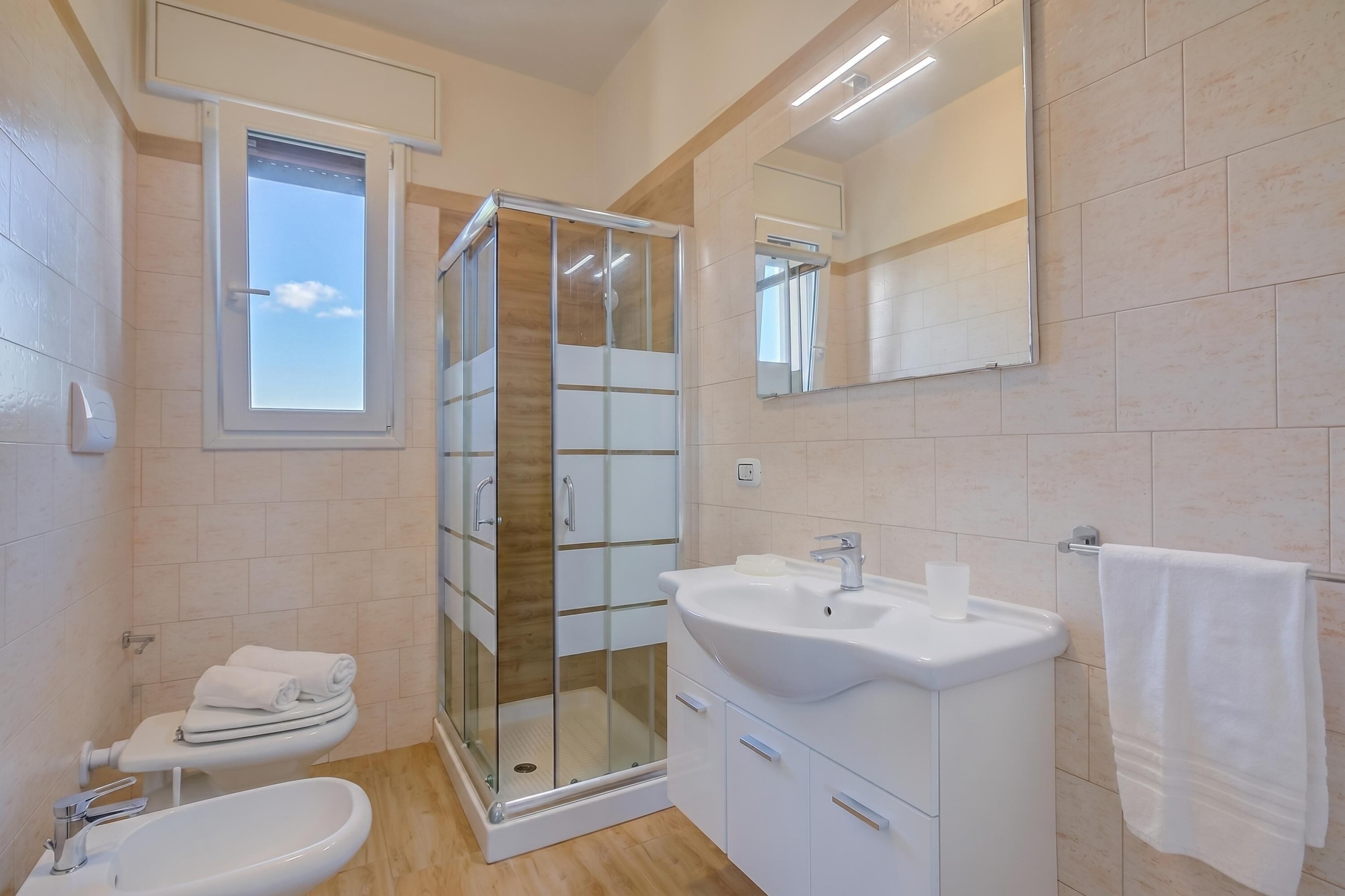 Une salle de bain moderne avec une douche à parois de verre, un lavabo, des toilettes et une fenêtre.