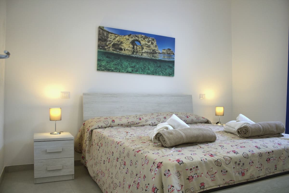 Une chambre à coucher avec un lit, une table de chevet, une lampe et un tableau au mur.