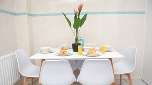 A dining table with white chairs, plates of food, a potted plant, and a juice box. - Gorgeous 3 bed in Bristol (Bradley Stoke)