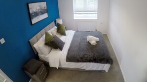 A bedroom with a bed, a window with blinds, a radiator, and a picture on the wall. - Gorgeous 3 bed in Bristol (Bradley Stoke)
