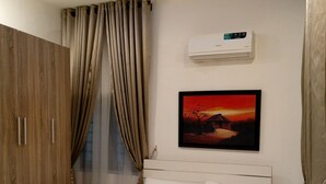 A bedroom with a bed, wooden wardrobe, and a painting on the wall. - Inviting 2-bed Apt With Parking in Ifako-ijaiye (Lagos)