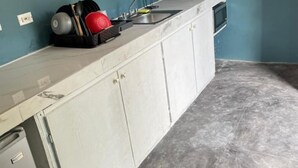A kitchen with a sink, cabinets, and a small refrigerator. - Bri's On The Beach (Treasure Beach)