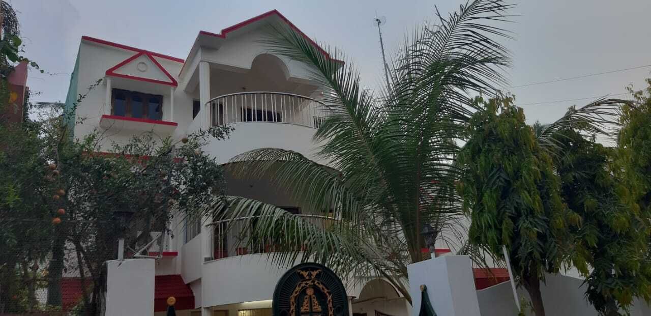 Un edificio a più piani con facciata bianca e dettagli rossi, dotato di balconi e un ingresso centrale con uno stemma decorativo.