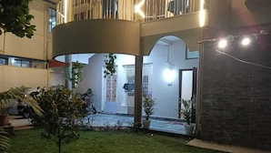 A courtyard with a small lawn, potted plants, and a motorcycle parked near the entrance. - HOTEL BHUBANESWAR PRIDE (Bhubaneshwar)