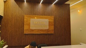 A hotel reception desk with a wooden panel wall and a sign that reads "HOTEL BHUBANESWAR PRIDE." - HOTEL BHUBANESWAR PRIDE (Bhubaneshwar)