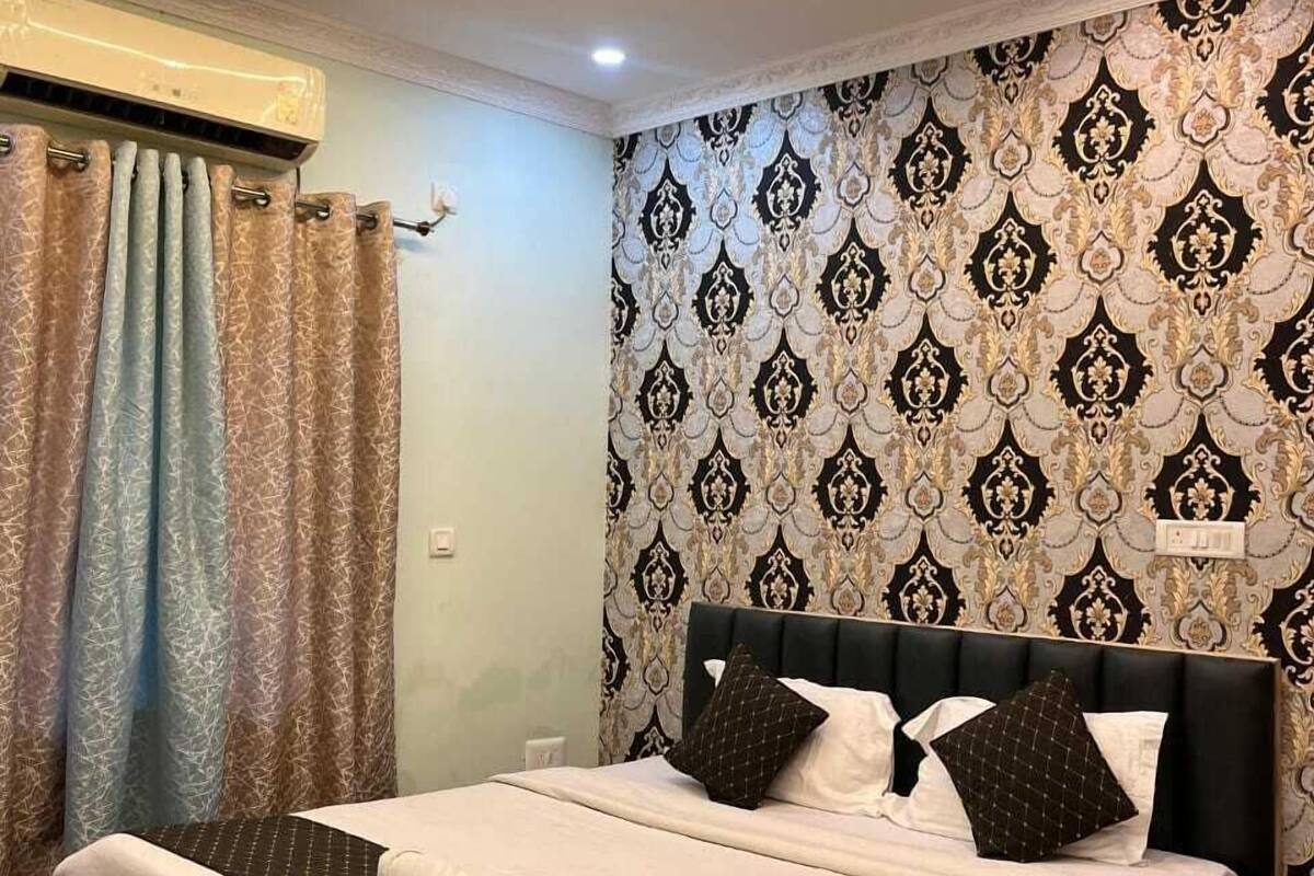 A bedroom with a bed, curtains, a patterned wall, and a ceiling fan.