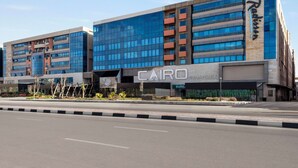 A modern hotel with a prominent 'CAIRO COMPLEX' sign, featuring a mix of glass and brick facade, and a 'Radisson' logo on the side. - Radisson Residences Cairo Heliopolis (Cairo)