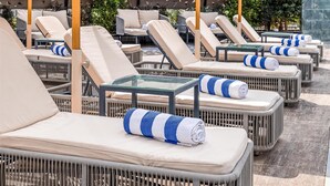 Outdoor lounge chairs with umbrellas, arranged in rows on a terrace. - Radisson Residences Cairo Heliopolis (Cairo)