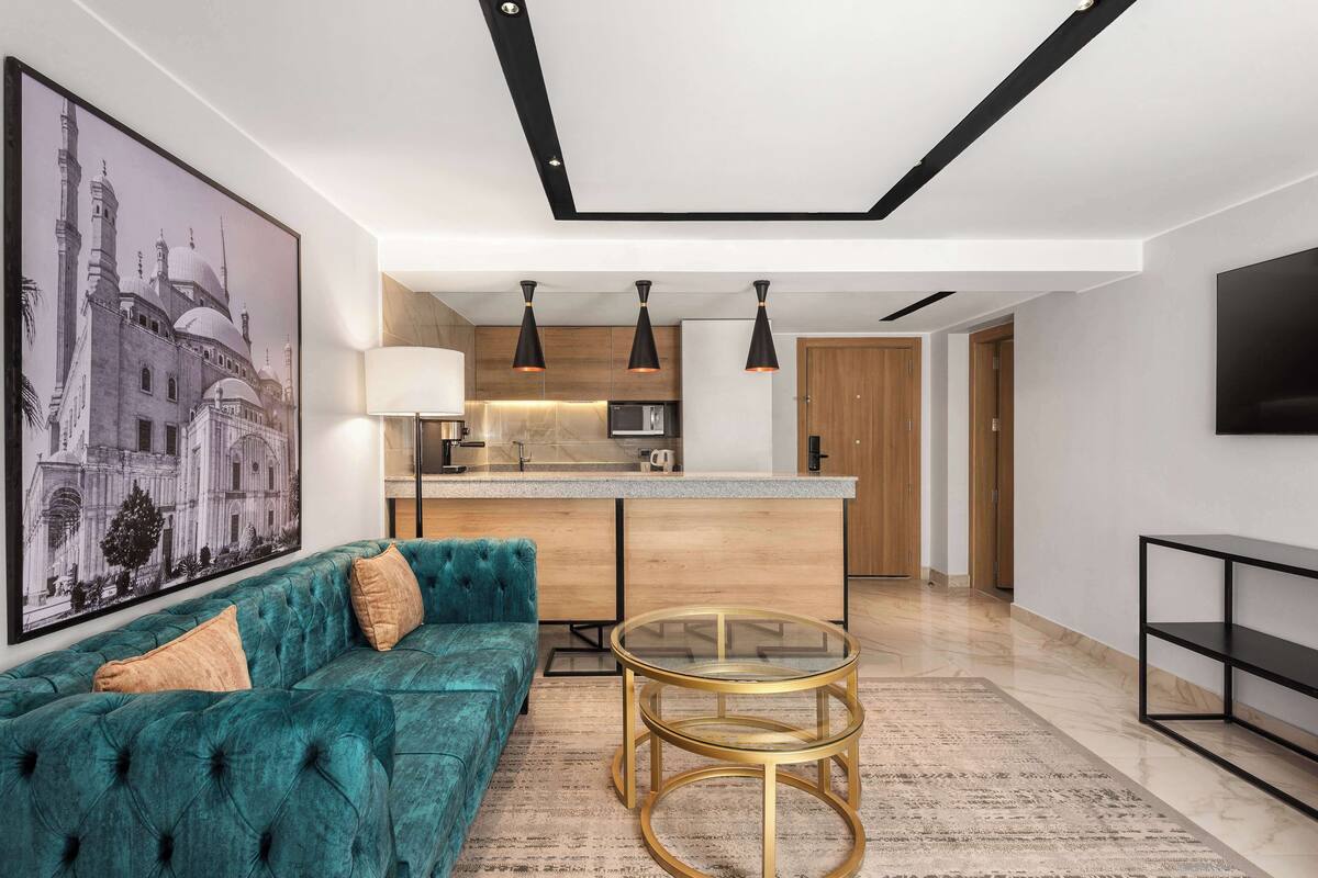 Una sala de estar moderna con un sofá color turquesa, una mesa de centro de vidrio y un cuadro grande en la pared.