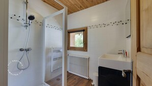 Une salle de bain avec une douche, une fenêtre, un radiateur et un lavabo.