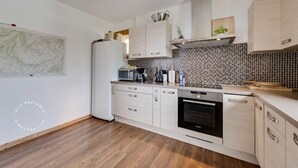 Une cuisine moderne avec des meubles blancs, un four Bosch et un four à micro-ondes.