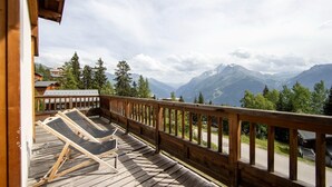Une terrasse en bois avec des chaises longues donnant sur un paysage montagneux.
