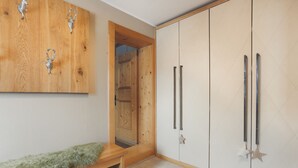 A room with a wooden bench, a wardrobe with two doors, and a mirror. - Apartment Aschbach - cosy for couples or families with 1-2 children  (Kitzbuhel)