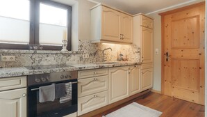 A kitchen with a stove, oven, sink, and wooden cabinets. - Apartment Aschbach - cosy for couples or families with 1-2 children  (Kitzbuhel)