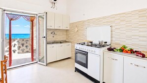 Una cucina con vista sul mare, completa di piano cottura, forno e zona pranzo con una sedia.