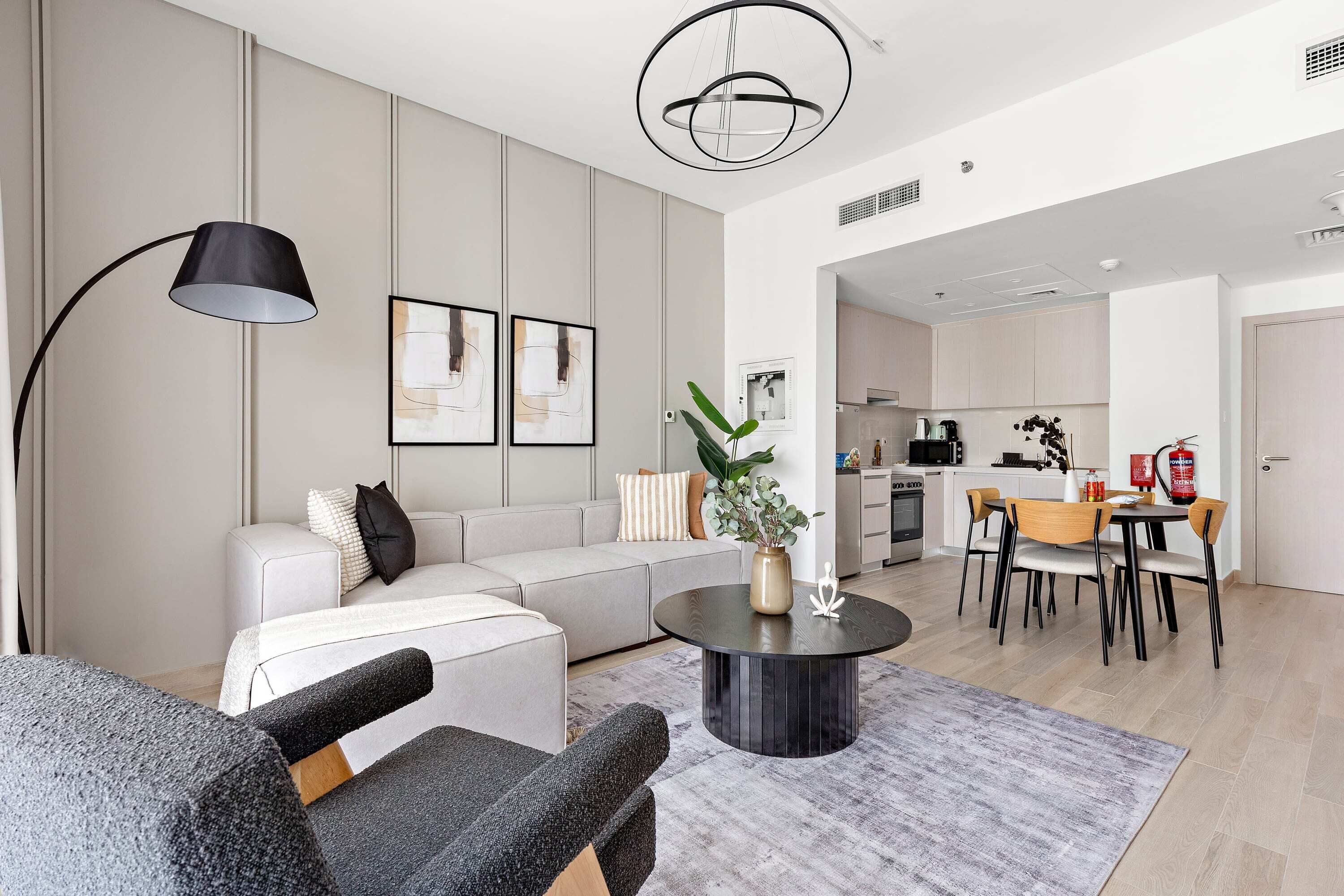 A modern living room with a sofa, coffee table, and dining area. There is a kitchen in the background.