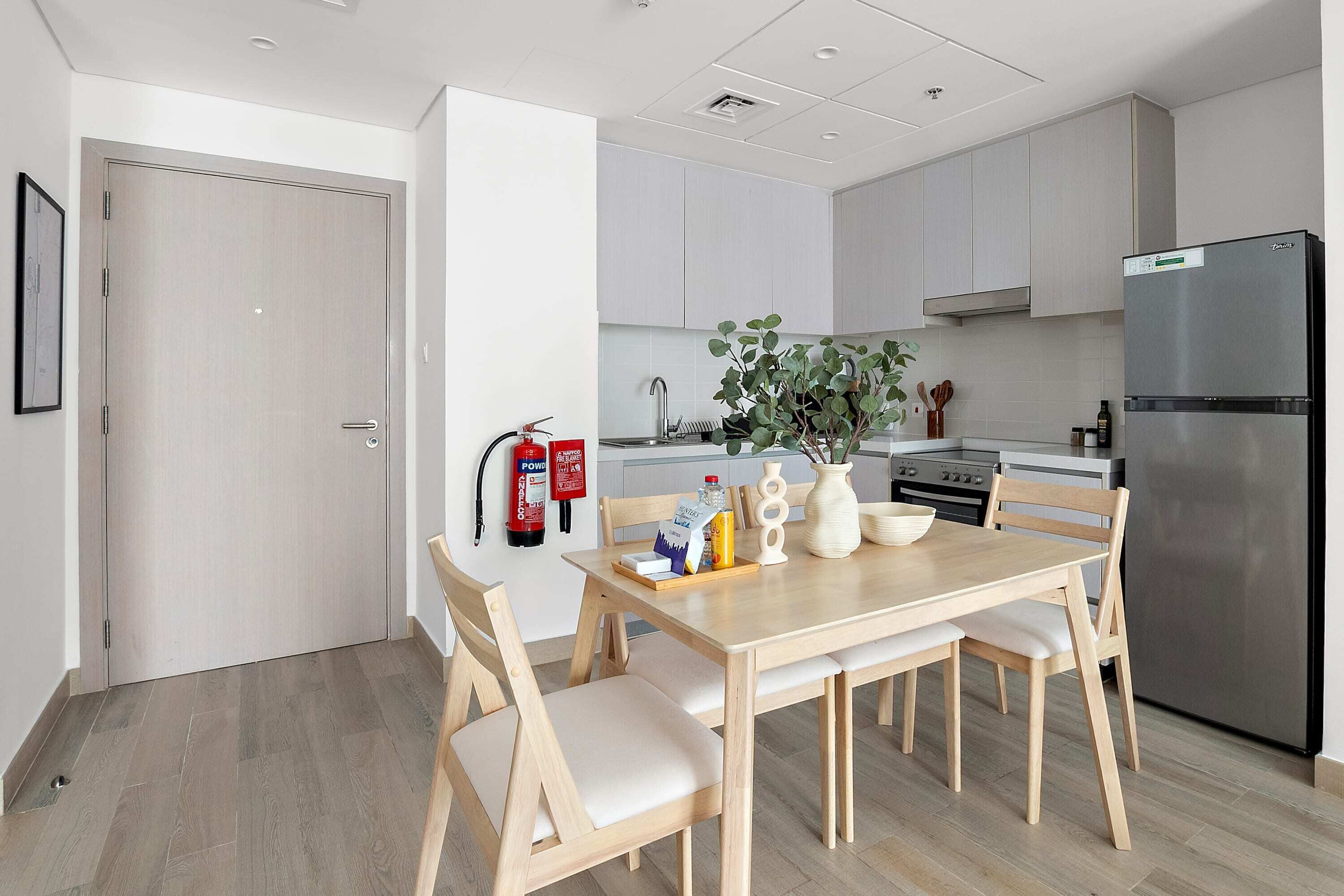 Een moderne keuken met houten kastjes, een roestvrijstalen koelkast en een eettafel met stoelen.