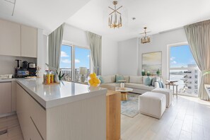 A modern apartment with a kitchen, living area, and large windows offering a view of the city. - Silkhaus Waters Edge Tower - Yas Island (Abu Dhabi)