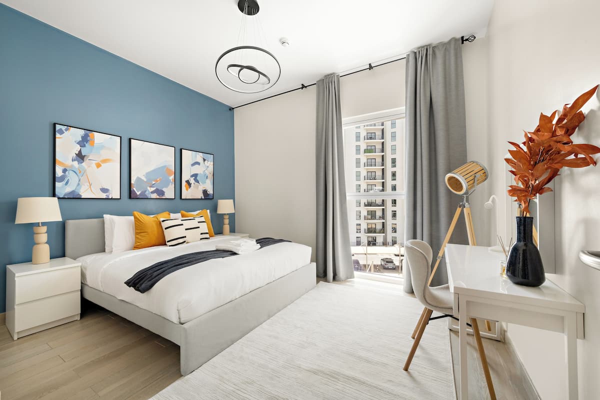 Un dormitorio moderno con cama, mesitas de noche, un escritorio y una silla.