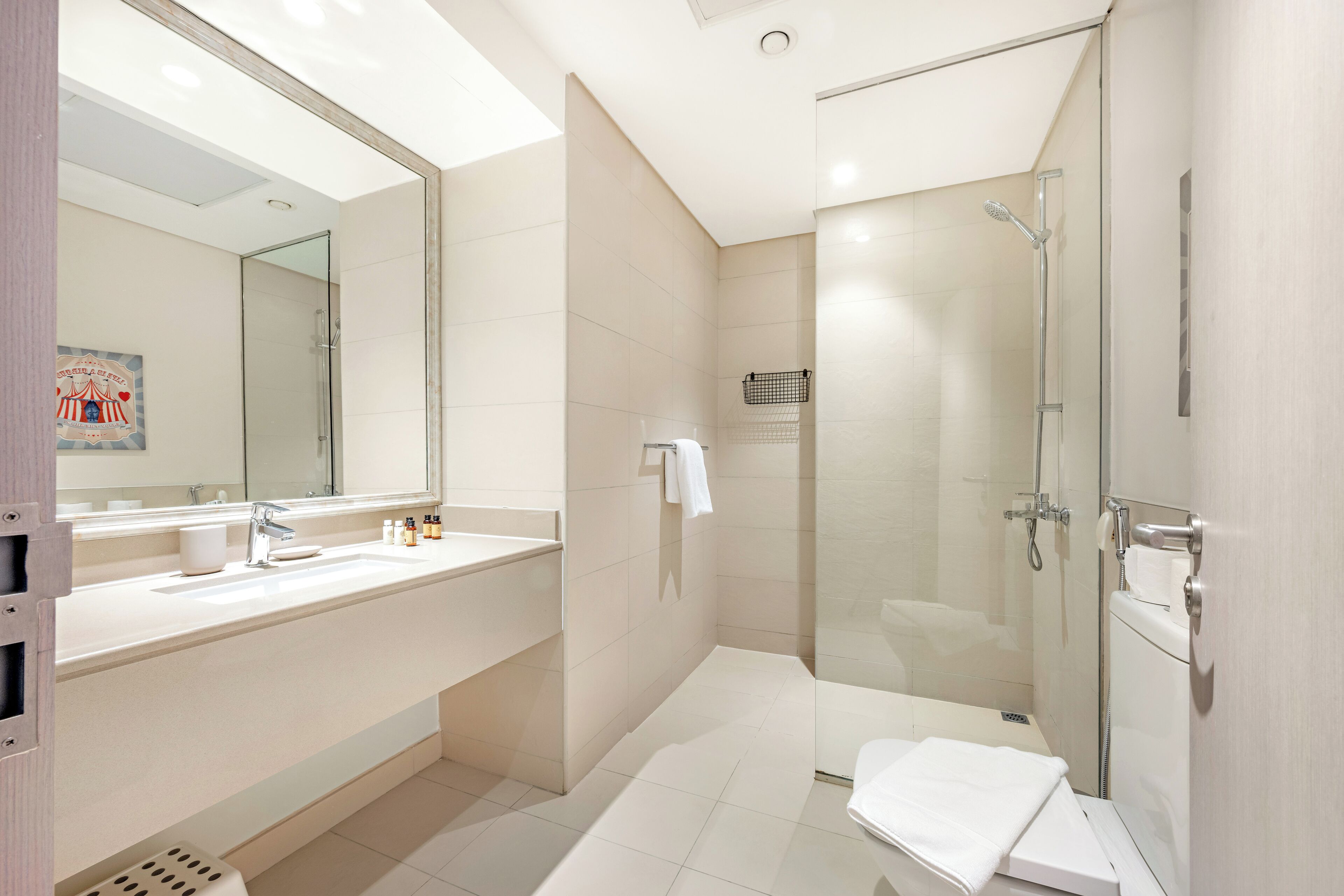 Een moderne badkamer met een grote spiegel, een douche met glazen wanden en een wit wastafelmeubel.
