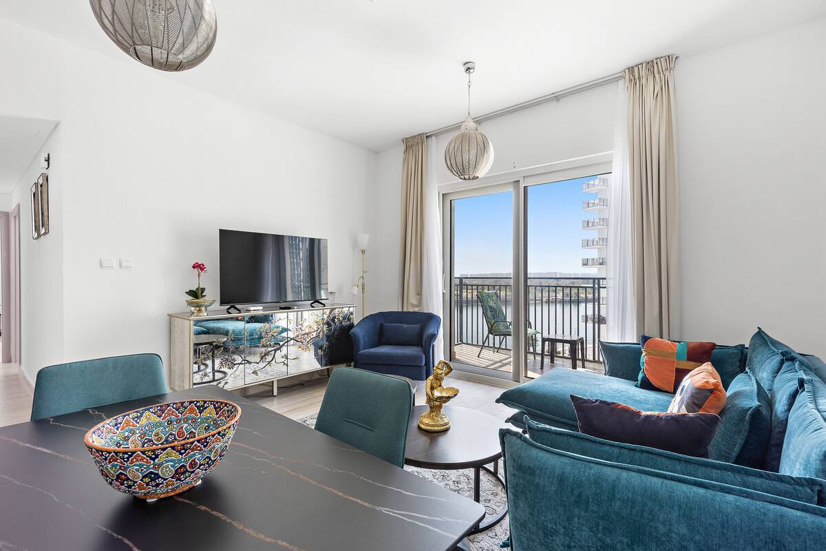 Una sala de estar moderna con una mesa de comedor, sofá y un balcón con vistas.