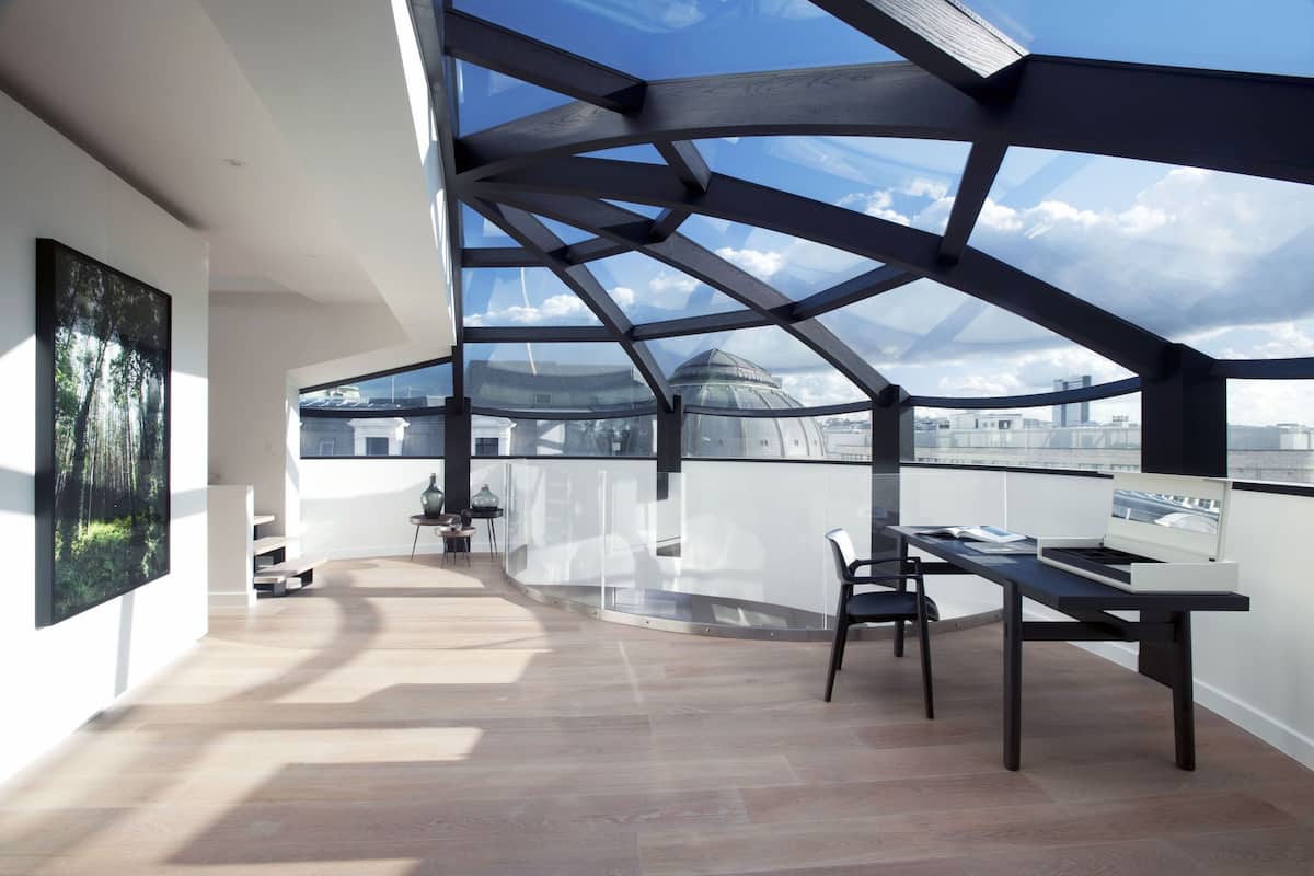 A modern interior with a glass ceiling, a dining area, and a view of the cityscape.