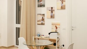 Un espace repas moderne avec une table en verre, des chaises blanches et un rideau beige.