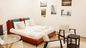 Une chambre d’hôtel moderne avec un lit, une table en verre, une chaise et des œuvres d’art accrochées au mur.