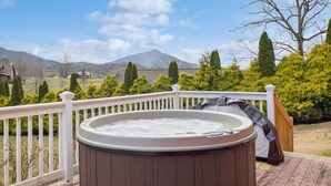 A hot tub on a wooden deck with a white railing, overlooking a mountainous landscape. - Majestic Valley Retreat 2 Bedroom Cabin by RedAwning (Sevierville)