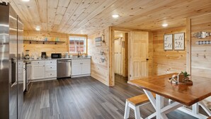 A modern kitchen with wooden walls, stainless steel appliances, and a wooden dining table. - Majestic Valley Retreat 2 Bedroom Cabin by RedAwning (Sevierville)