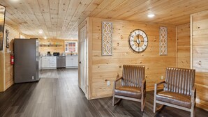 A wooden cabin interior with a kitchen area, two wooden chairs, a wall clock, and a fire extinguisher. - Majestic Valley Retreat 2 Bedroom Cabin by RedAwning (Sevierville)