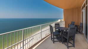 A balcony with a view of the ocean, equipped with a table and chairs.