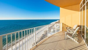 A balcony with a view of the ocean, white chairs, and a tiled floor. - Phoenix Gulf Towers 2002 2 Bedroom Condo (Orange Beach)