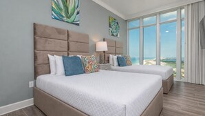 A bedroom with two beds, a large window with a view, and artwork on the walls. - Phoenix Gulf Towers 2601 4 Bedroom Condo (Orange Beach)