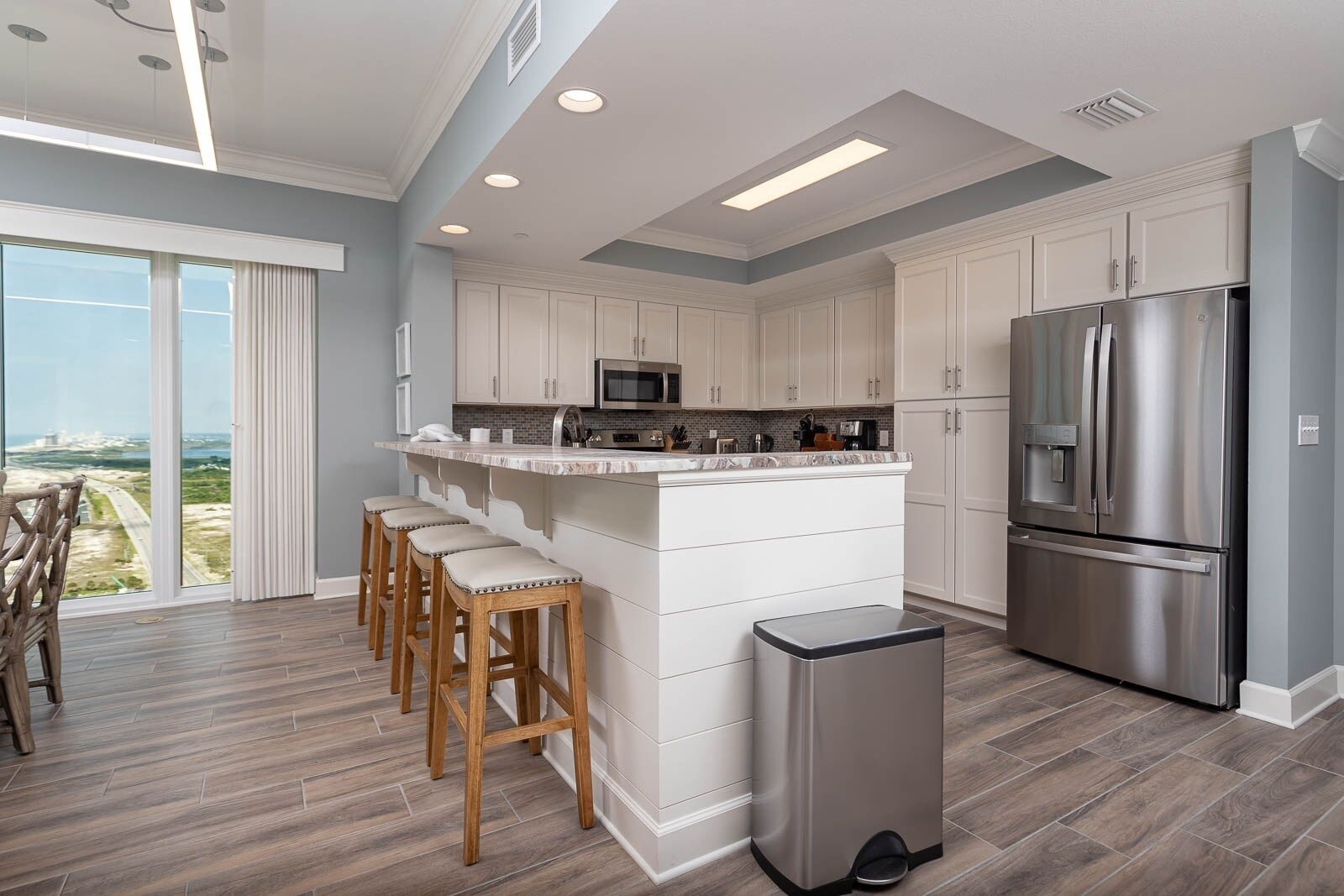 A modern kitchen with a central island, stainless steel appliances, and a view of the ocean.