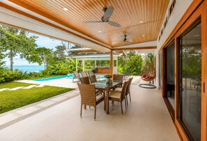 Une terrasse extérieure moderne, dotée d’une piscine, d’un espace repas et offrant une vue sur l’océan.