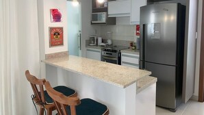 Une cuisine moderne dotée d’un îlot central, d’appareils électroménagers en acier inoxydable et de luminaires suspendus.