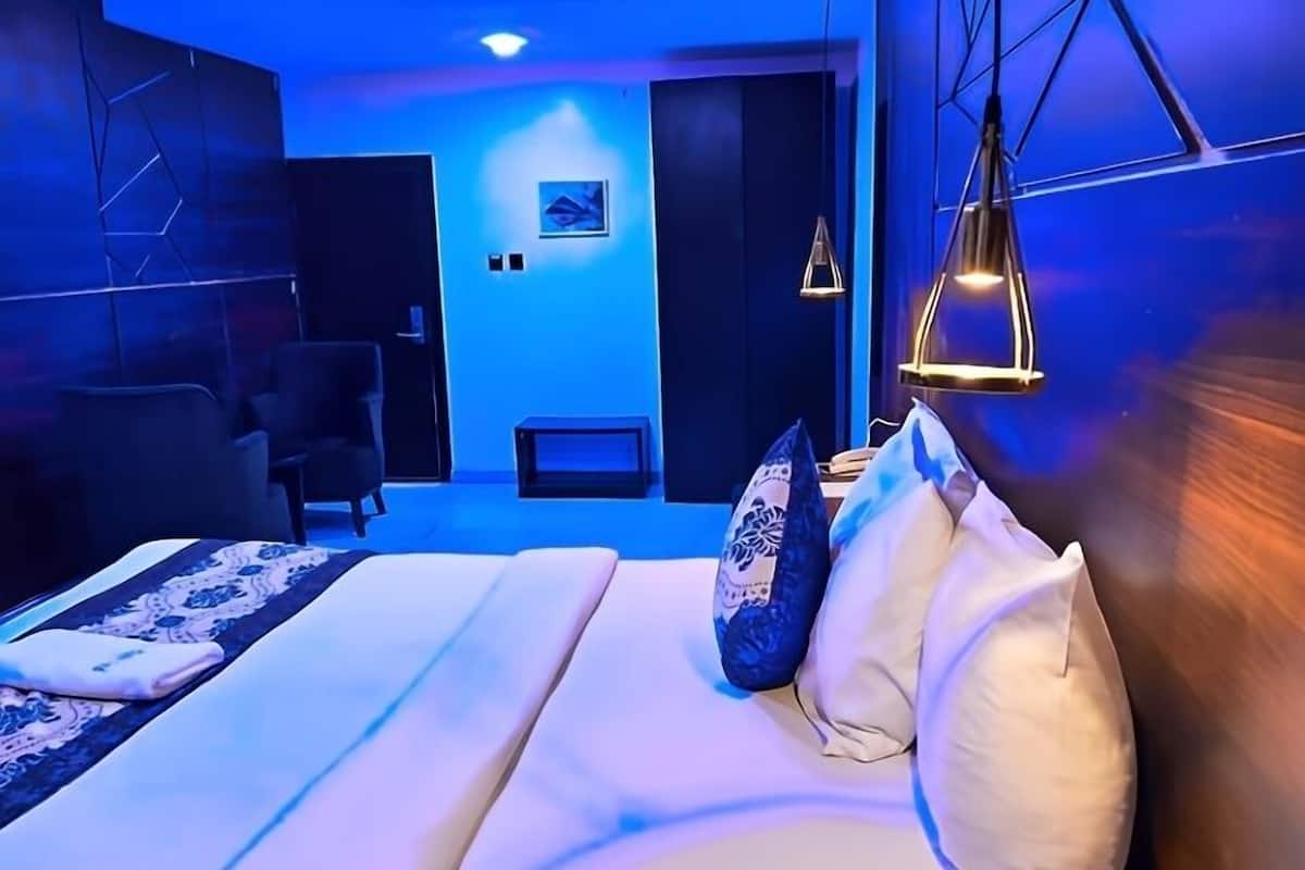 A modern bedroom with a large bed, a desk, and a chair.