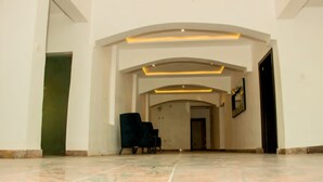 A spacious lobby with a marble floor, a black armchair, and a framed picture on the wall. - Water Ripples Hotel (Lekki)